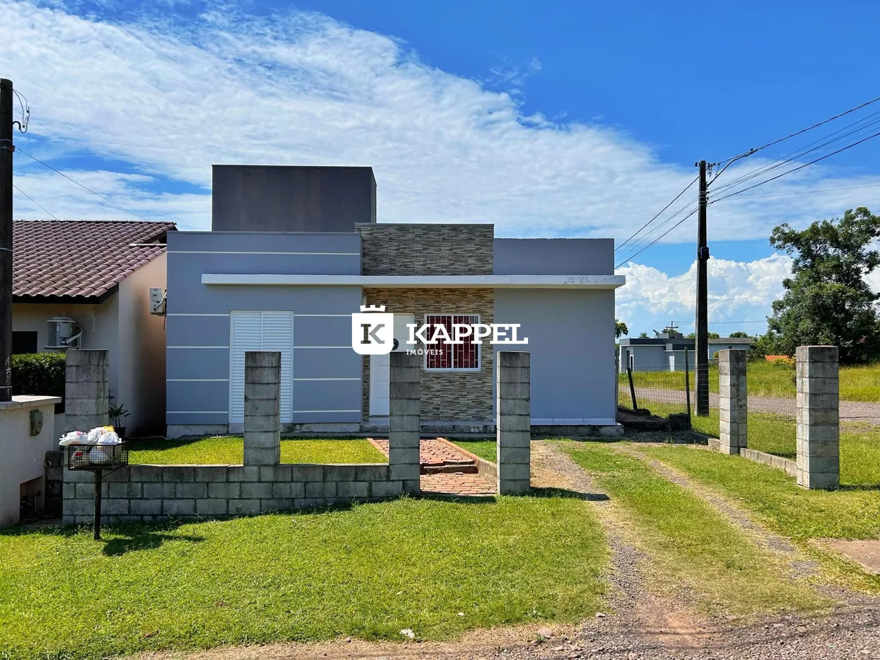 Fachada externa de uma residência em Lajeado, Brasil, com muro de contenção e gramado.