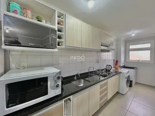 Foto de uma cozinha com armários brancos e bancada escura.