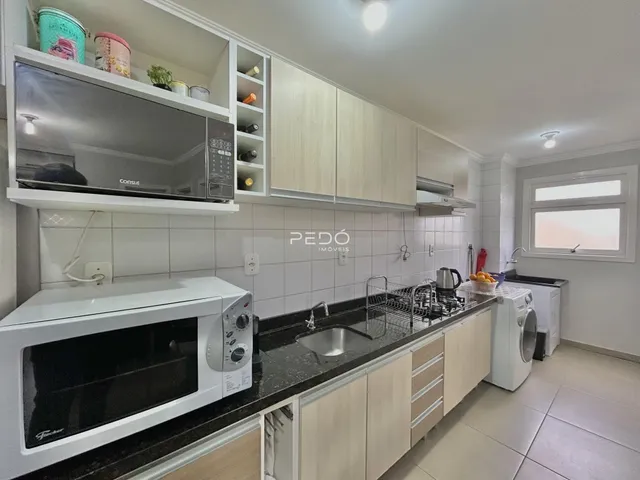 Foto de uma cozinha com armários brancos e bancada escura.