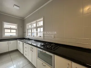 Uma cozinha com armários brancos e bancada escura.