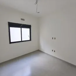 Ambiente interno com paredes brancas e uma janela no centro.