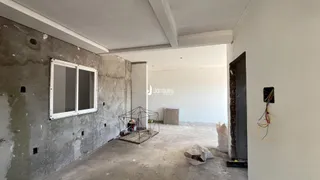 Interior de uma sala em construção com paredes de concreto aparente.