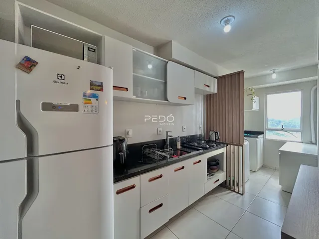 Cozinha moderna com armários brancos e bancadas escuras.