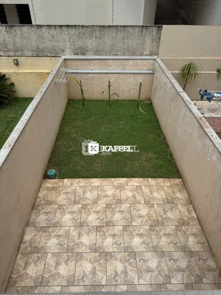 Área externa com piso de ladrilhos claros e gramado.