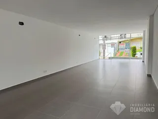 Interior de um espaço amplo com piso de cerâmica e paredes brancas.