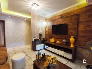 Sala de estar com painel de madeira e televisão montada na parede.