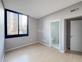 Ambiente interno com piso de madeira clara e grande janela.