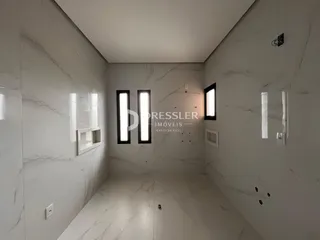 A foto mostra um corredor interno com paredes brancas e piso de mármore.