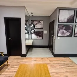 Foto do interior de uma sala com piso de madeira e paredes cinzas.