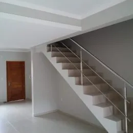 Foto de um corredor com escadaria branca e paredes claras.