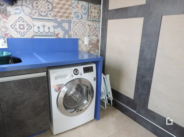 Interior de um cômodo com armários azuis e máquina de lavar roupa.