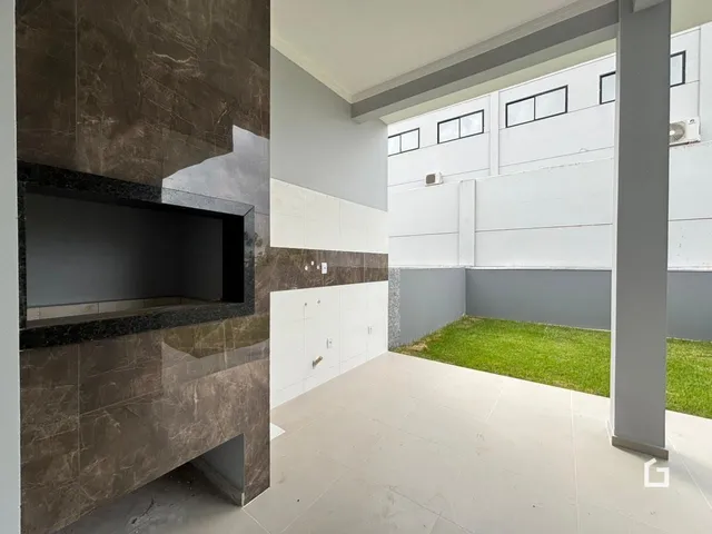 Imagem de um ambiente interno com parede de destaque e área externa gramada.