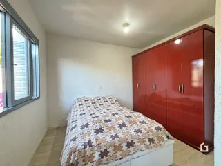 Quarto com armário de madeira e janela em um imóvel no Brasil.