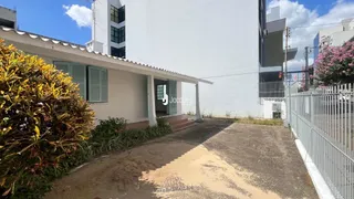 Vista da fachada de uma residência com cerca e vegetação no jardim.
