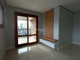 Interior de uma sala com porta de madeira e piso claro.