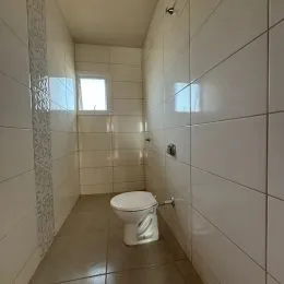 Foto de um banheiro com paredes brancas e piso de cerâmica.