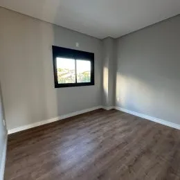 Vista interna de um cômodo com piso de madeira e janela.
