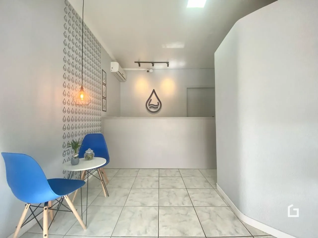 Imagem de um corredor interno com piso de cerâmica clara e decoração de parede.