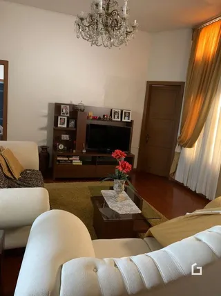 Foto de uma sala de estar interna com piso de madeira e lustre.