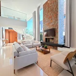 Sala de estar com sofá claro e piso de madeira clara em um imóvel.
