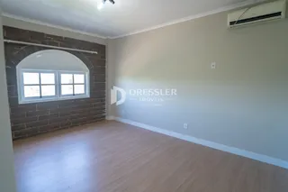 Ambiente interno de uma sala com parede de tijolos aparentes e piso de madeira clara.