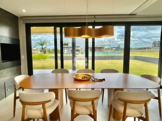 Mesa de jantar de madeira com cadeiras em uma sala de estar com vista para o jardim.
