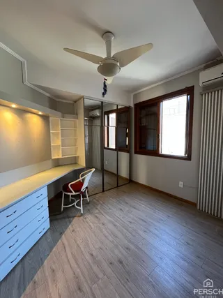 Uma sala de estar com piso de madeira e estantes brancas.