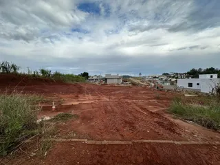 Vista aérea de um terreno aberto com solo avermelhado e vegetação rasteira.