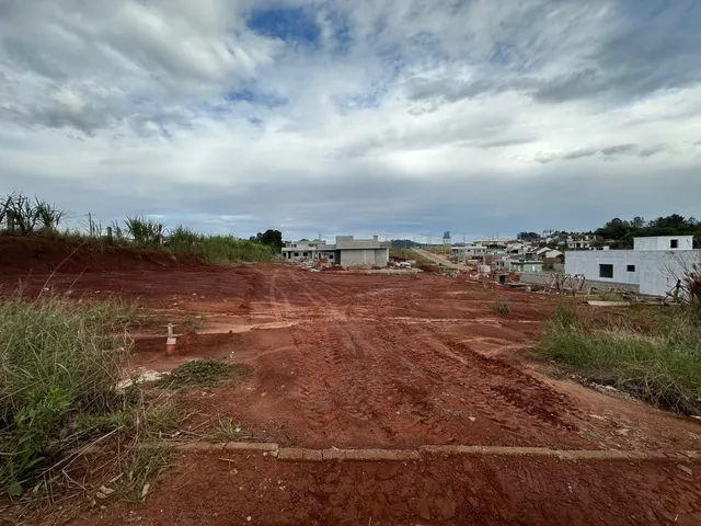 Vista aérea de um terreno aberto com solo avermelhado e vegetação rasteira.