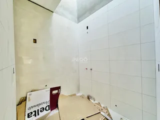 Vista de um ambiente interno com paredes brancas e revestimento de cerâmica.
