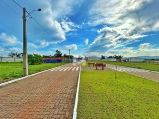 Vista da fachada de uma propriedade com gramado e estrada no Brasil.