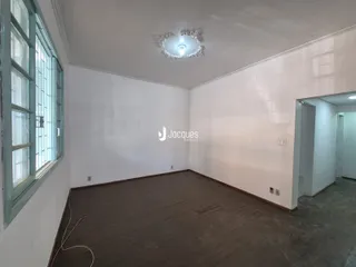 Ambiente interno de uma sala com piso de madeira e paredes brancas.