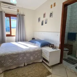 Quarto com cama de casal e paredes claras.
