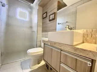 Banheiro com box de vidro e bancada de mármore.