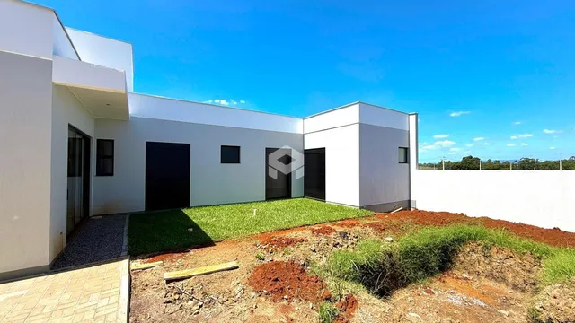 Fachada de uma casa moderna branca com jardim em terra.