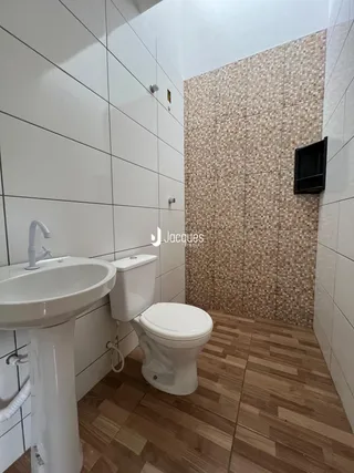 Interior de um banheiro com revestimento de azulejos brancos e piso de madeira.