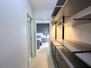 A foto mostra um corredor interno com piso de madeira clara e armários embutidos.
