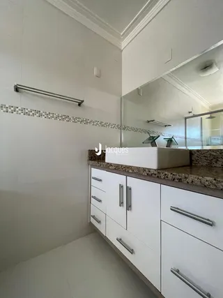 Foto de um banheiro com revestimento de azulejo e armários brancos.