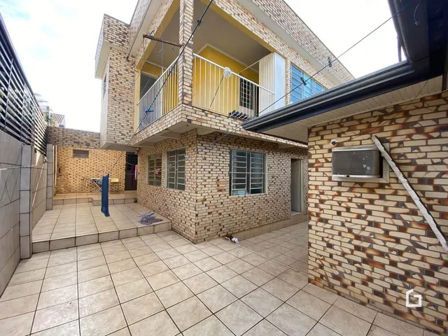 Vista da fachada de uma residência em tijolo aparente com terraço.