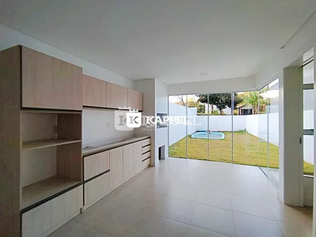 Ambiente interno com armários de madeira e vista para um jardim com piscina.