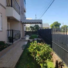Vista externa de um jardim com gramado e cerca em uma propriedade.