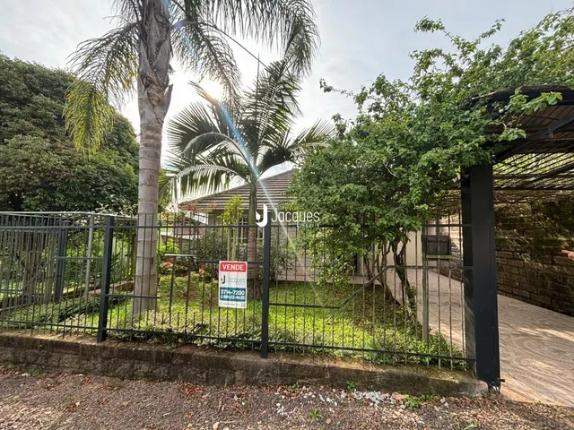 Foto da fachada de uma propriedade com cerca e vegetação.