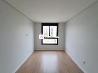 Vista interna de um cômodo com piso de madeira clara e grande janela.