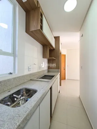 Vista da cozinha com armários e bancadas claras.