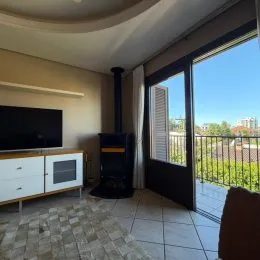 Sala de estar com televisão e grandes janelas que dão para o exterior.