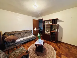 Sala de estar com sofá e piso de madeira em um imóvel no Brasil.