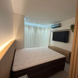 Quarto com cama e cortinas claras em um imóvel.