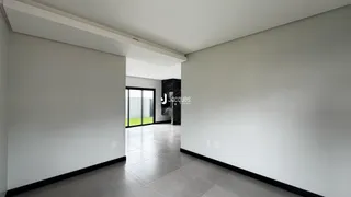 Um corredor interno com paredes brancas e piso claro.