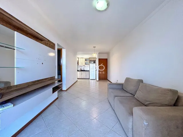 Sala de estar com piso de cerâmica clara e sofá de cor neutra.