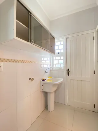 Foto de um banheiro com pia branca e porta branca.